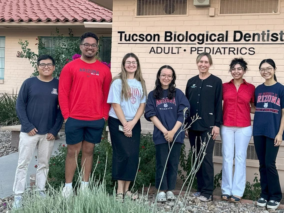 Six students pose for a photo outside a dentist's office with the dentist.