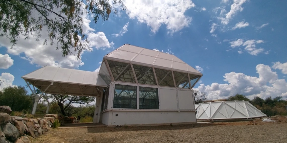 a building with large windows against a blue sky flecked with clouds.