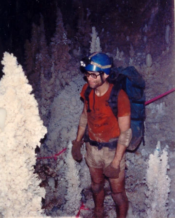Bert Schneider stands inside a cave, outfitted with gear