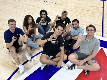 group of students, seated on basketball court